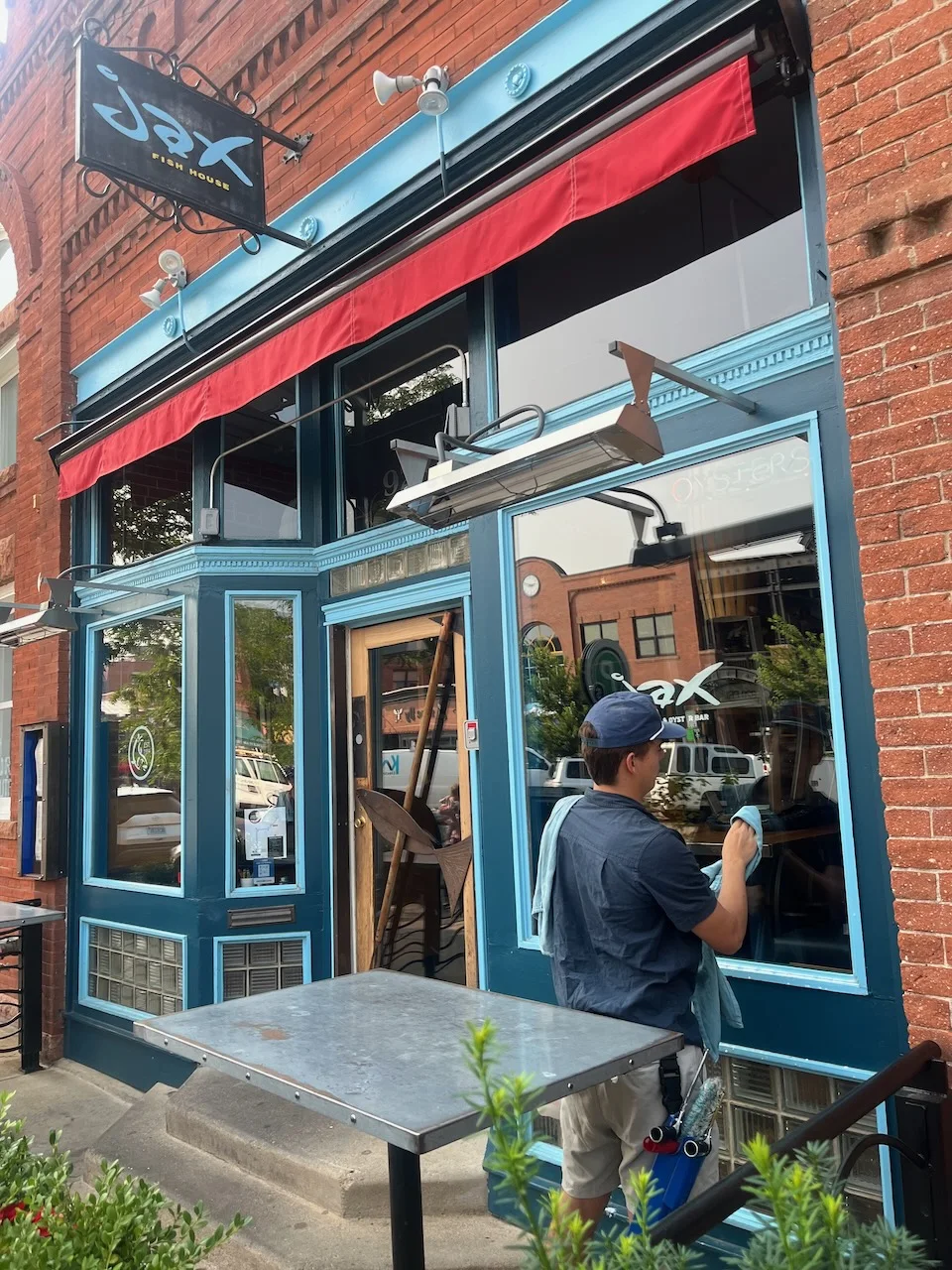 Happy Glass worker cleaning a Jax Fish House window closeup in Boulder, Colorado