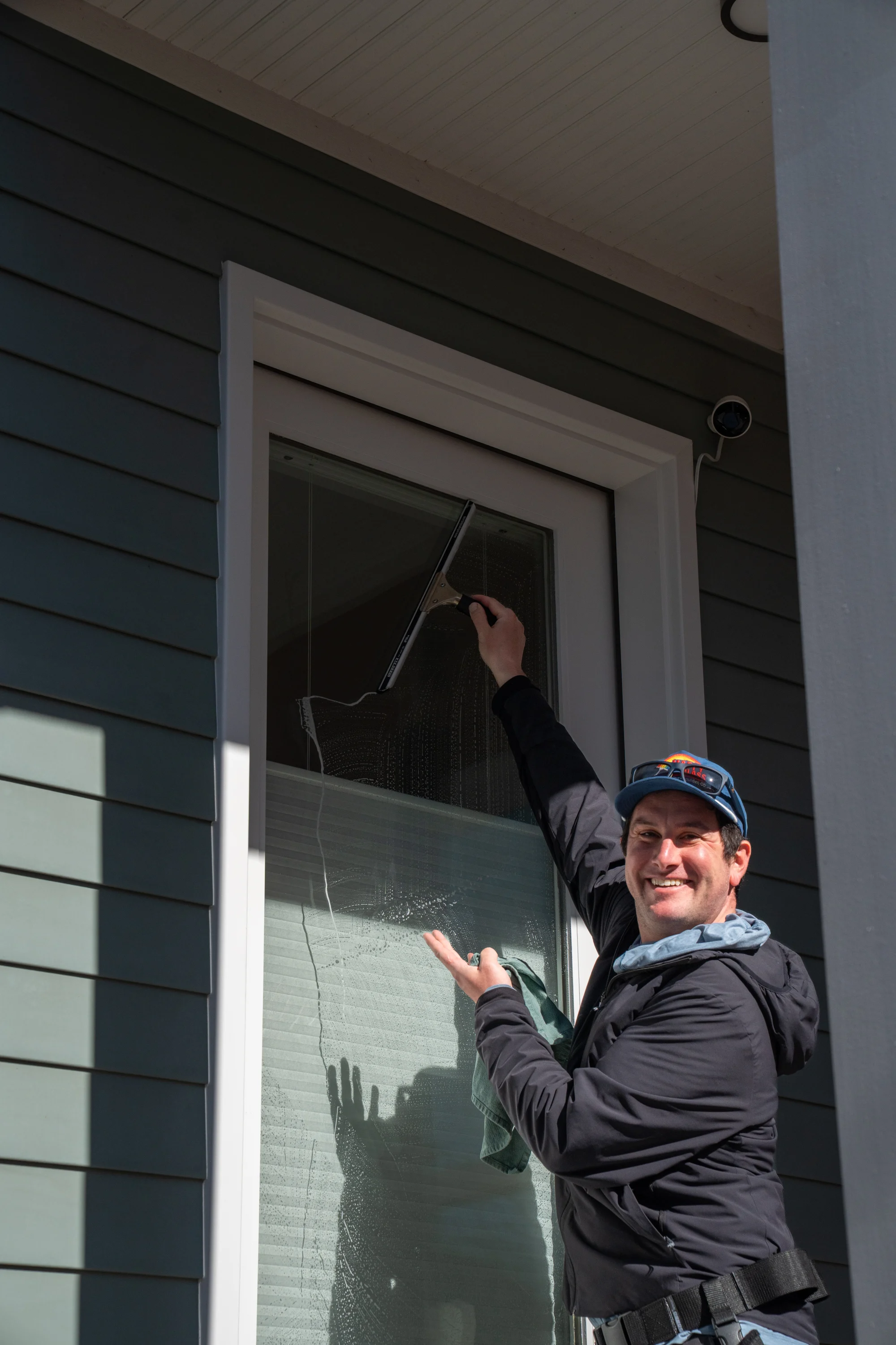 Happy Glass team member cleaning a residential window near Louisville, Colorado